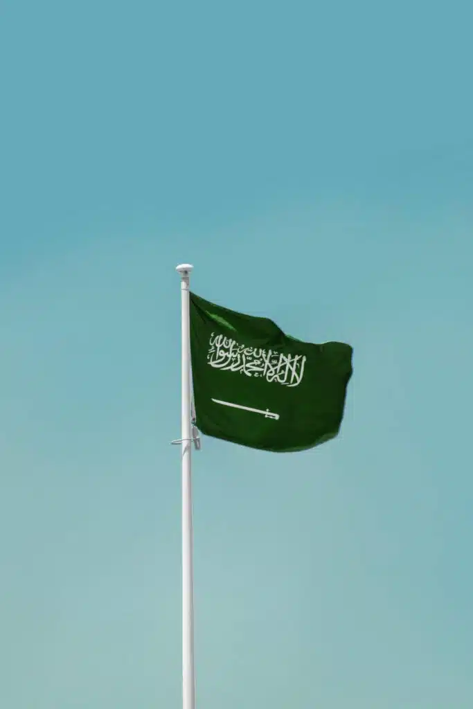 National flag of Saudi Arabia waving on a flagpole against a clear blue sky in Riyadh.